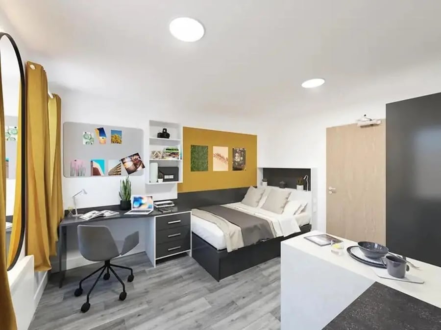 Bed desk chair shelves laptop and kitchen counter bedroom at Depot Point in London Student Accommodation