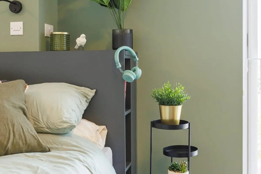 Bed with green pillows and headphones bedroom at Element Bermondsey in London Student Accommodation