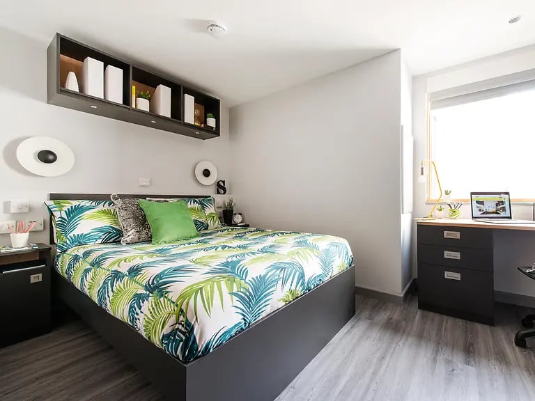 Bed with tropical bedding desk and laptop bedroom at Yugo Therese House in London Student Accommodation