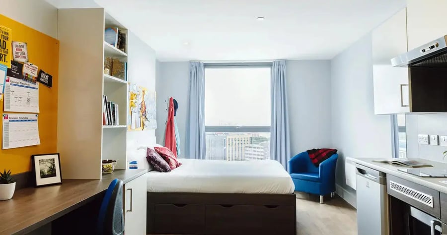 Bed desk shelving blue chair kitchen area studio at Kaplan Living Bournemouth in Bournemouth Student Accommodation