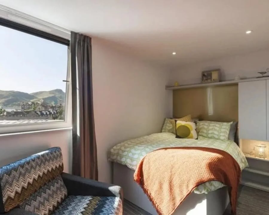 Bed with patterned bedding and armchair Bedroom at New Park in Edinburgh Student Accommodation
