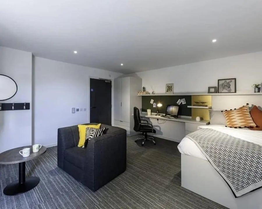 Desk bed armchair coffee table bedroom at New Park in Edinburgh Student Accommodation