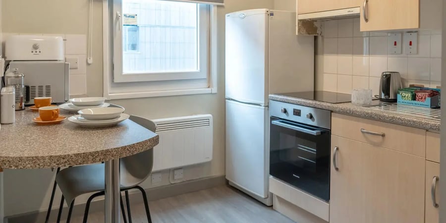 Table with cups plates toaster fridge oven kitchen at The Heights in Birmingham Student Accommodation