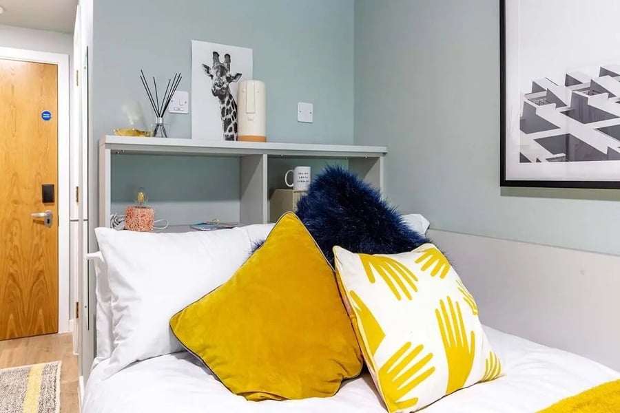 Bed with yellow and blue pillows study area at The Refinery in Leeds Student Accommodation