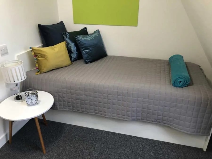 Bed alarm clock lamp pillows and rolled towel bedroom at Tudor Studios in Leicester Student Accommodation