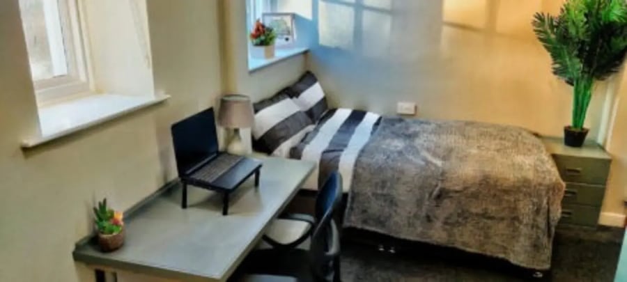 Desk with laptop bed with pillows bedroom at St Mary's Newcastle in Newcastle Upon Tyne Student Accommodation