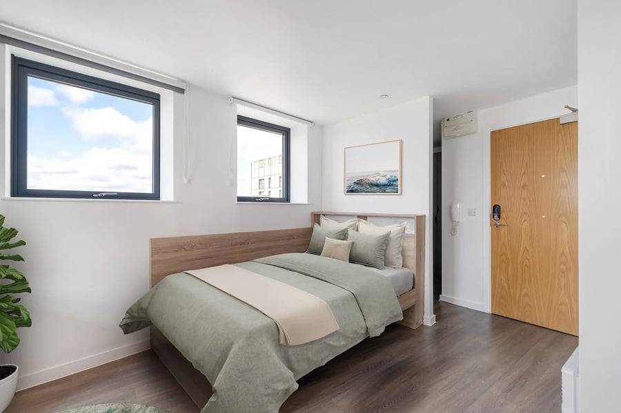 Bed with green bedding and wooden headboard bedroom at Canvas Walthamstow in London Student Accommodation