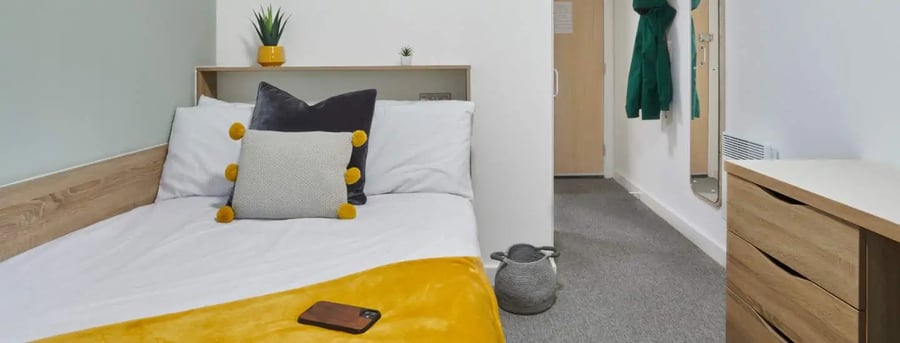 Bed with pillows and yellow throw bedroom at Sky Blue Point in Coventry Student Accommodation