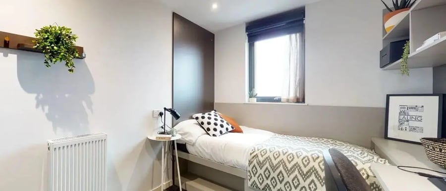 Bed with patterned blanket side table lamp and window bedroom at Chapter Ealing in London Student Accommodation