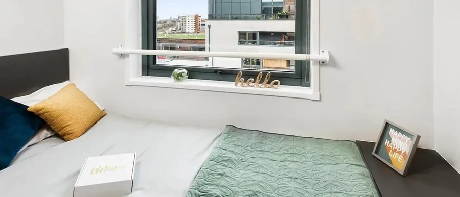 Bed with pillows, quilt, window, welcome box Bedroom at Chapter Islington in London Student Accommodation