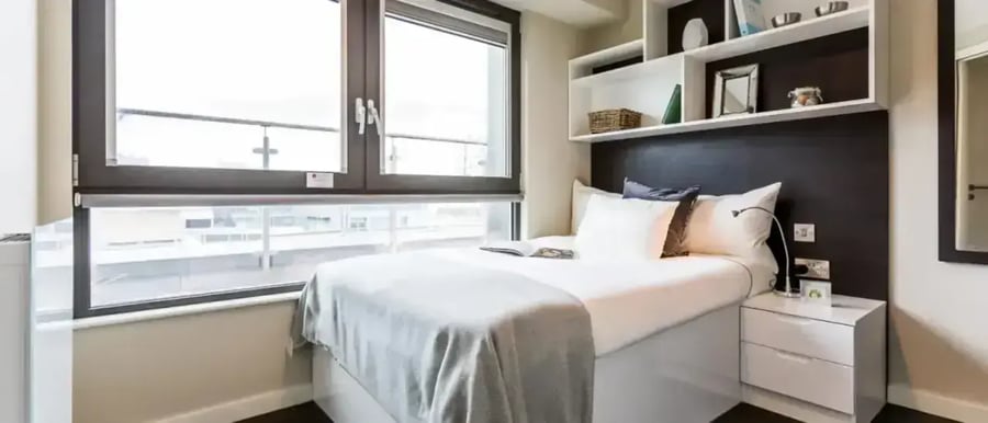 Bed bedside table and shelves bedroom at Chapter Old Street in London Student Accommodation