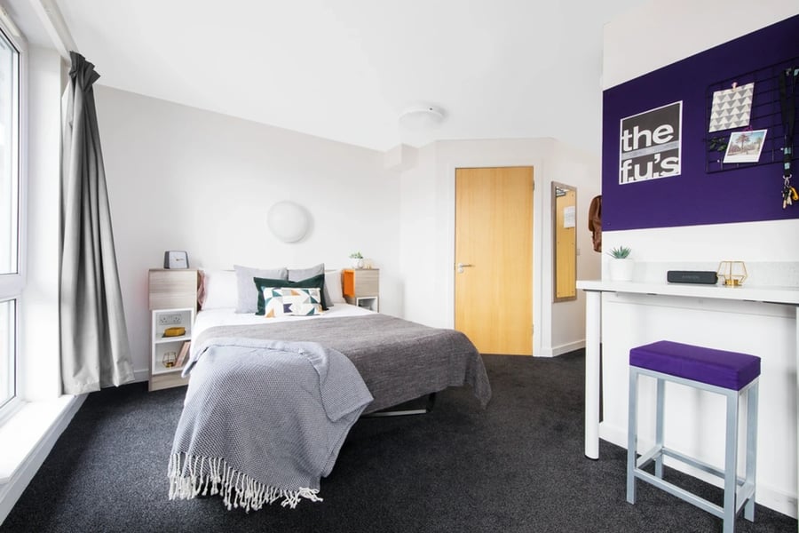 Bed with grey throws bedside table door Study area Bedroom at Queen's Park House in Coventry Student Accommodation