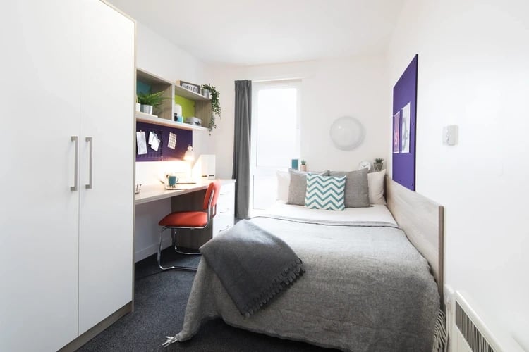 Bed desk wardrobe and purple noticeboard bedroom at Queen's Park House in Coventry Student Accommodation