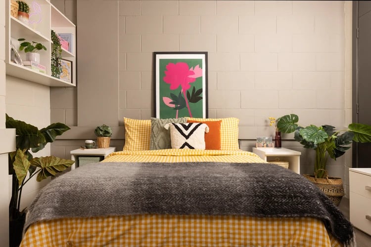 Bed with yellow checkered bedding artwork plants bedroom at Spring Gardens in Aberdeen Student Accommodation