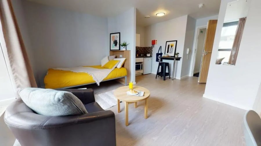 Bed armchair small kitchen and desk living room at iQ Sterling Court in London Student Accommodation