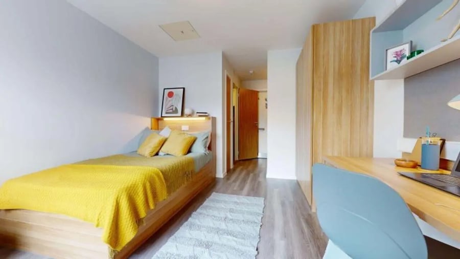 Bed with yellow blanket study desk and chair bedroom at iQ Sterling Court in London Student Accommodation
