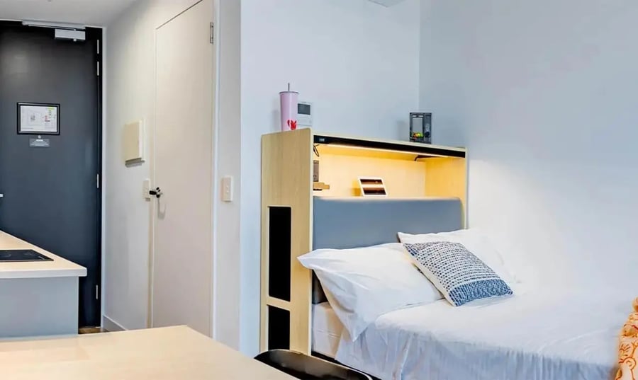 Bed with patterned pillow and desk area bedroom at The Switch Melbourne Victoria Market in Melbourne Student Accommodation