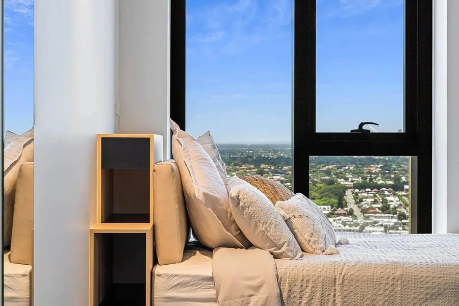 Bed with pillows near shelves and window bedroom at Perth Central in Perth Student Accommodation