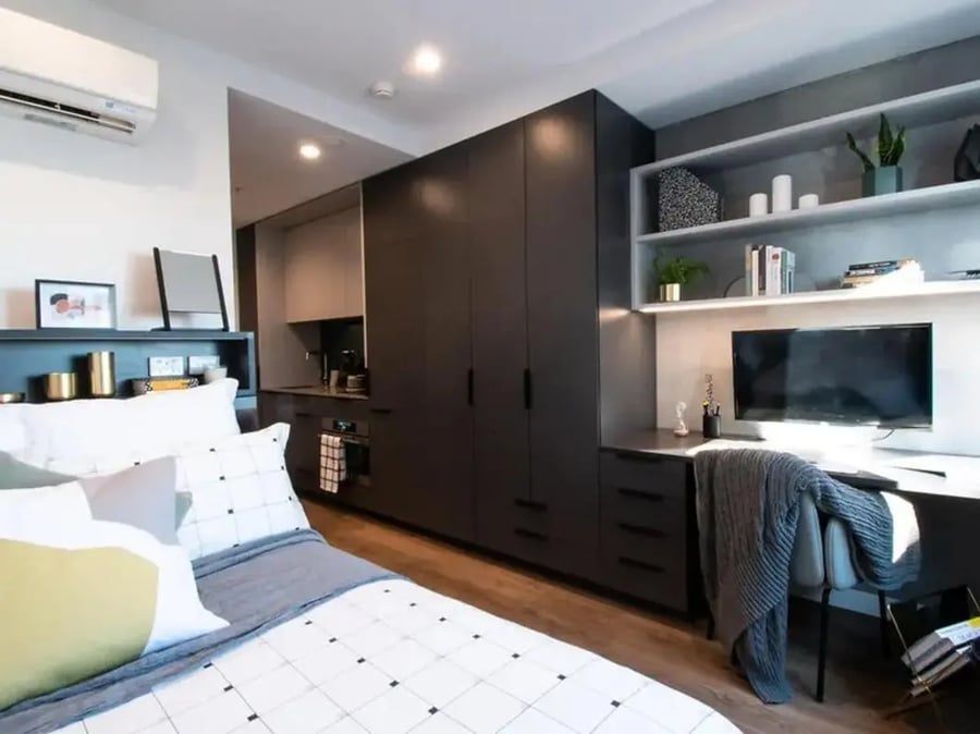 Bed wardrobe desk and kitchen area studio at Yugo University Square Melbourne in Melbourne Student Accommodation