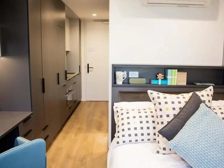 Bed with pillows and bookshelf bedroom at Yugo University Square Melbourne in Melbourne Student Accommodation