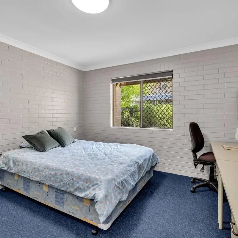 Bed with blue covers desk and chair bedroom at Murdoch University Village in Perth Student Accommodation