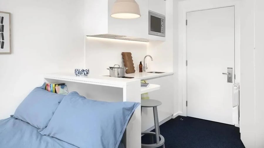 Blue pillows bed shelf cooking station kitchen studio at Scape Mile End in London Student Accommodation