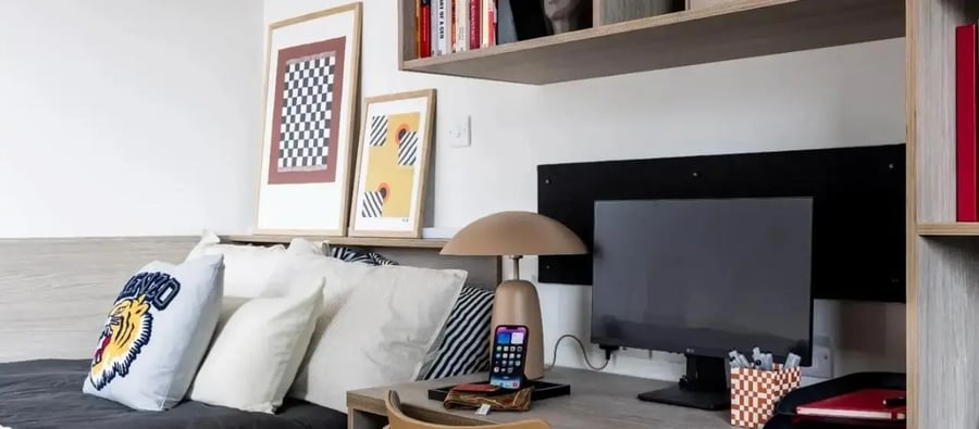 Cushioned bed desk with monitor and artwork Bedroom at Chapter London Bridge in London Student Accommodation
