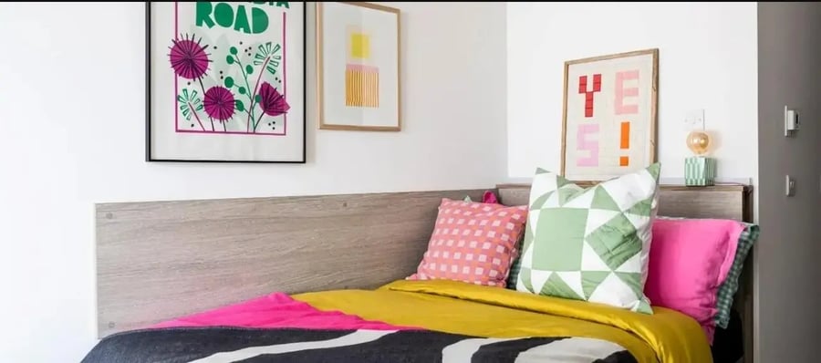Colorful pillows on bed with wall art bedroom at Chapter London Bridge in London Student Accommodation