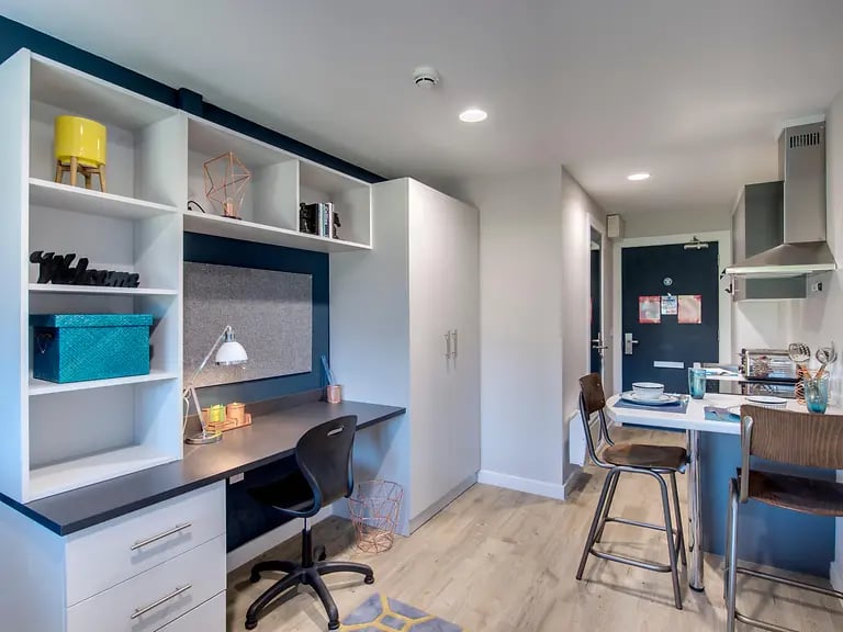 Desk shelves chair and kitchenette kitchen area at Riverside Quay in Stirling Student Accommodation