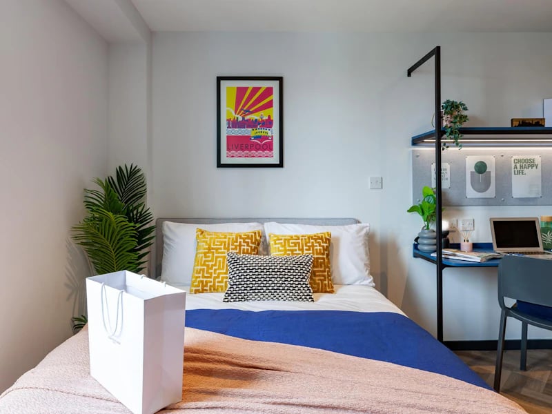 Bed with yellow pillows desk with laptop bedroom at Limelight in Liverpool Student Accommodation