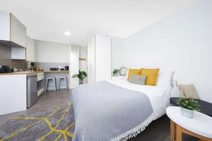 Bed kitchen appliances and stools studio apartment at Collegiate Merlin Heights in Leicester Student Accommodation