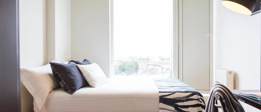 Bed with dark pillows and patterned throw bedroom at Chapter Spitalfields in London Student Accommodation