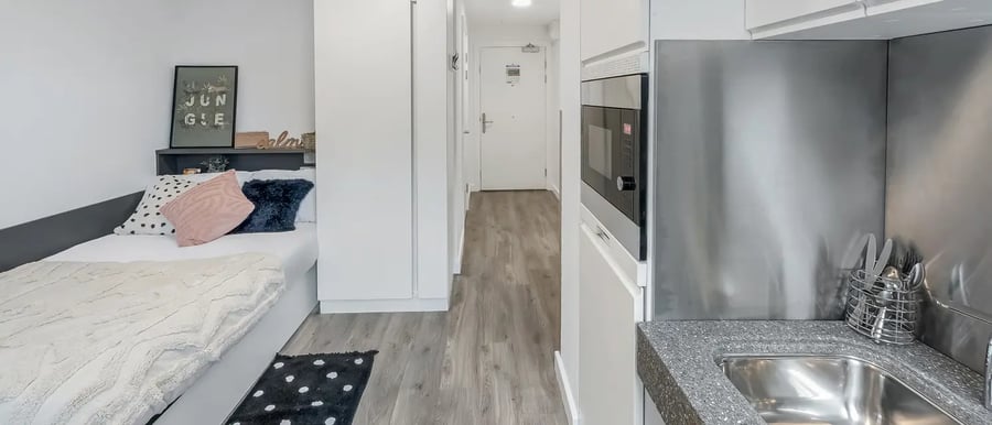 Bed with pillows kitchen counter sink microwave Bedroom kitchen at Chapter White City in London Student Accommodation
