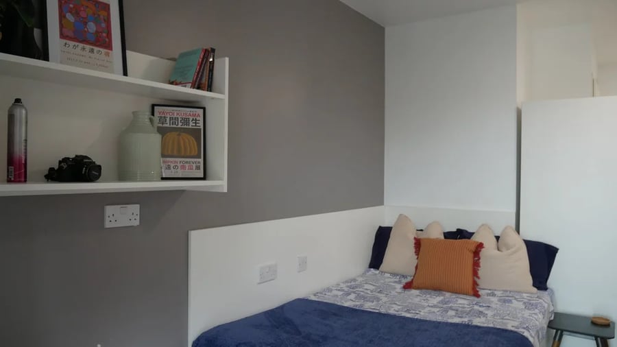 Bed with decorative pillows and wall shelf Bedroom at Theatre House in Coventry Student Accommodation