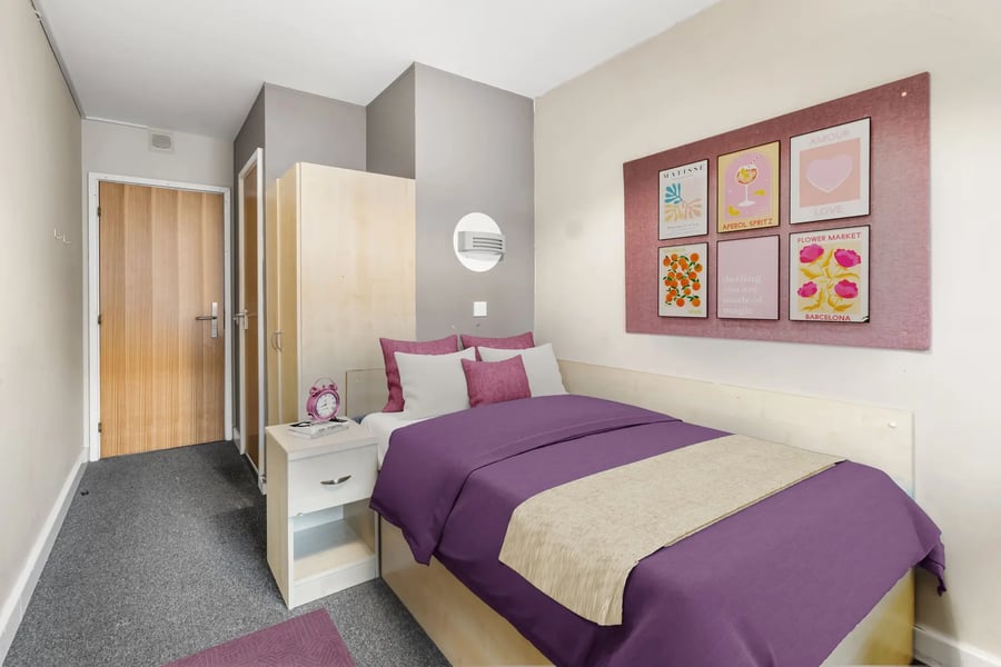 Bed with purple duvet bedside table artwork bedroom at The Heights in Birmingham Student Accommodation