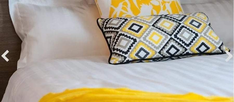 Bed with patterned pillows and yellow throw bedroom at Student Living D2 in Melbourne Student Accommodation