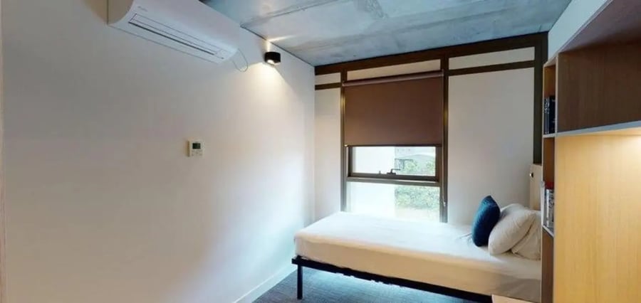 Bed, pillows, shelving, AC unit, window, bedroom at Unilodge Melbourne City in Melbourne Student Accommodation