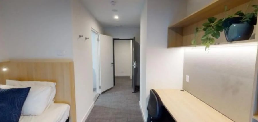 Bed desk shelf plant and hallway bedroom study area at Unilodge Melbourne City in Melbourne Student Accommodation