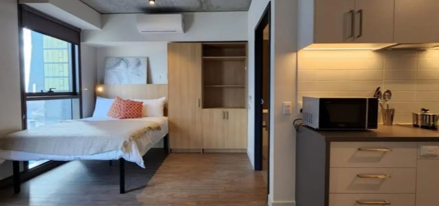 Bed microwave closet and window studio apartment at Unilodge Melbourne City in Melbourne Student Accommodation