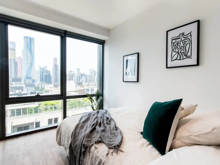 Bed with throw blanket and city view bedroom at Yugo Berkeley Street in Melbourne Student Accommodation
