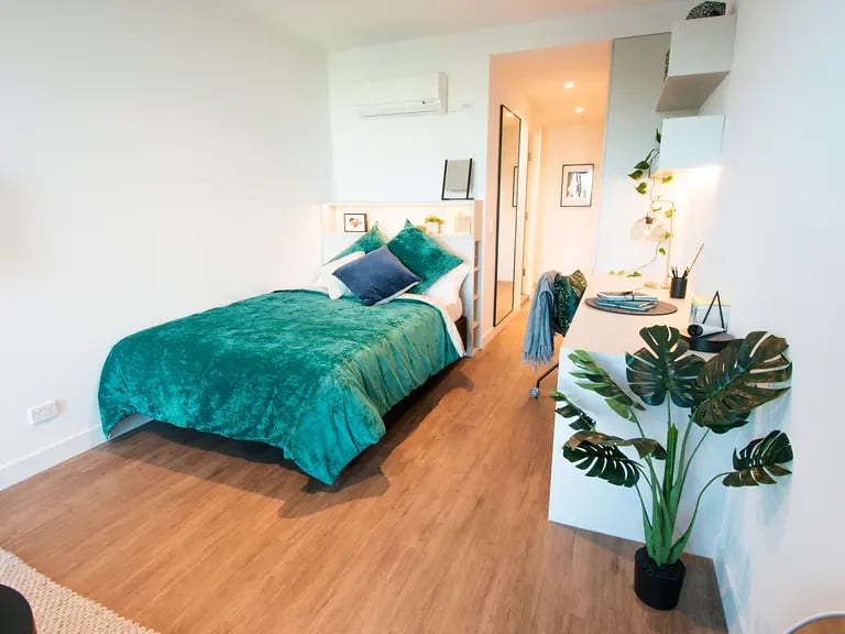 Bed study area with desk and plant bedroom at Yugo Berkeley Street in Melbourne Student Accommodation