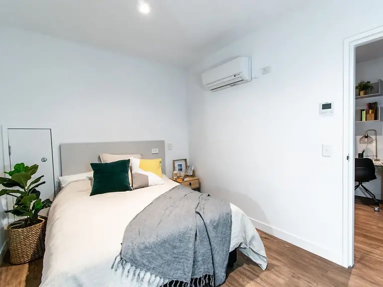 Bed pillows throws plant air conditioner bedroom at Yugo Berkeley Street in Melbourne Student Accommodation