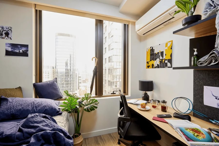 Bed desk plant and city view bedroom at Scape La Trobe in Melbourne Student Accommodation