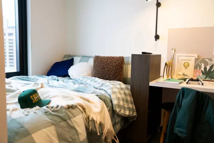 Bed with green hat pillows desk with giraffe decor bedroom at Scape Cornell Place in Melbourne Student Accommodation