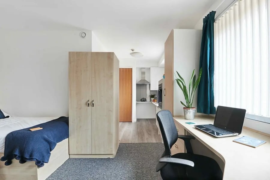 Bed desk wardrobe plant kitchen study area at Bernard Myers House in London Student Accommodation