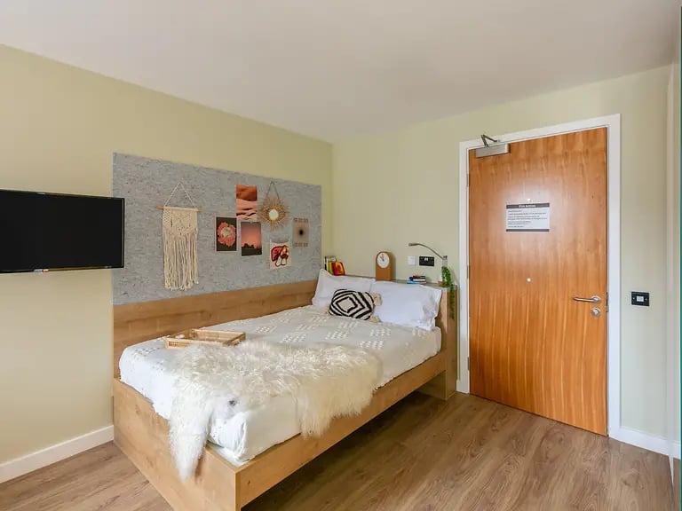 Bed TV bulletin board and door bedroom at The Curve in London Student Accommodation