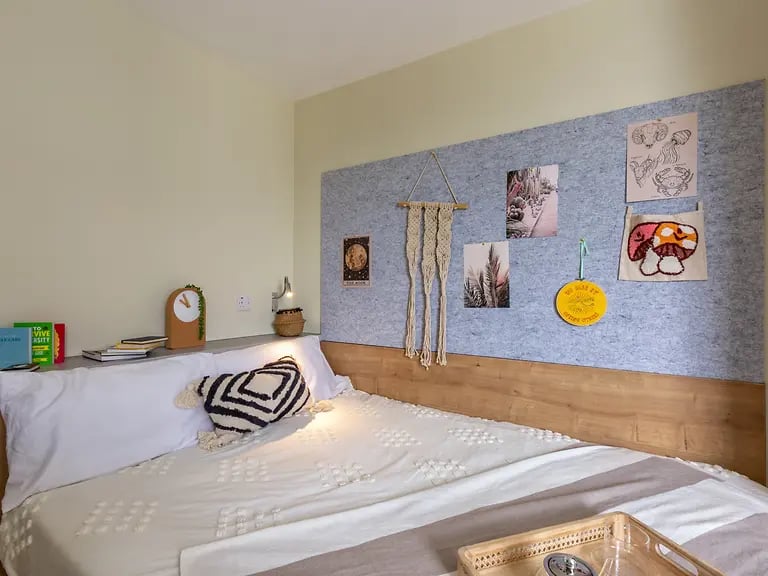 Bed with pillows books clock and wall art bedroom at The Curve in London Student Accommodation