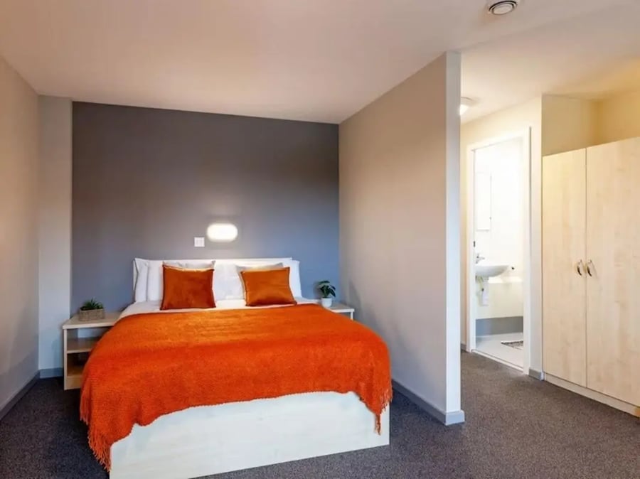 Bed with orange throw twin pillows and wardrobe bedroom at Crown House - Reading in Reading Student Accommodation