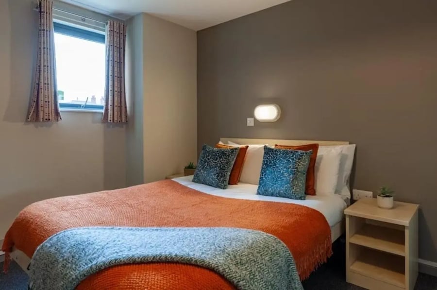 Bed with orange throw and blue pillows bedroom at Crown House - Reading in Reading Student Accommodation
