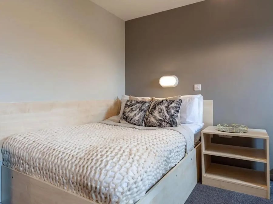 Bed with textured blanket two pillows bedside table bedroom at Crown House - Reading in Reading Student Accommodation